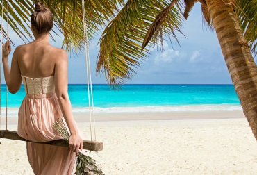 Woman sitting on a swing on a beautiful beach